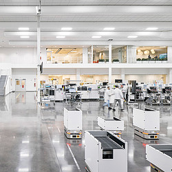 A person in a white coat standing next to several white machines.